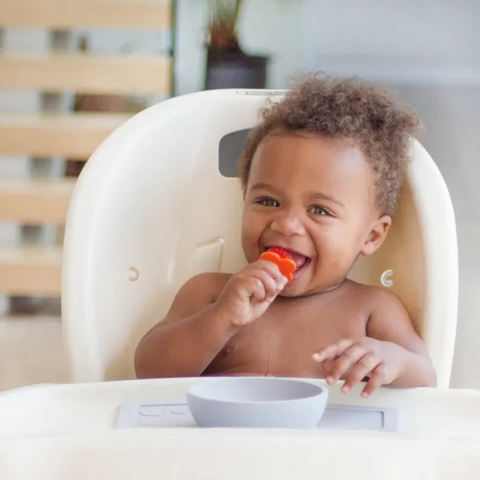 A happy baby eating with a grabease infant spoon
